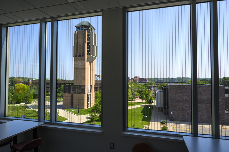 An interior view of a wide window patterned with long stripes, or bird-safe glass, with a view of a clock tower