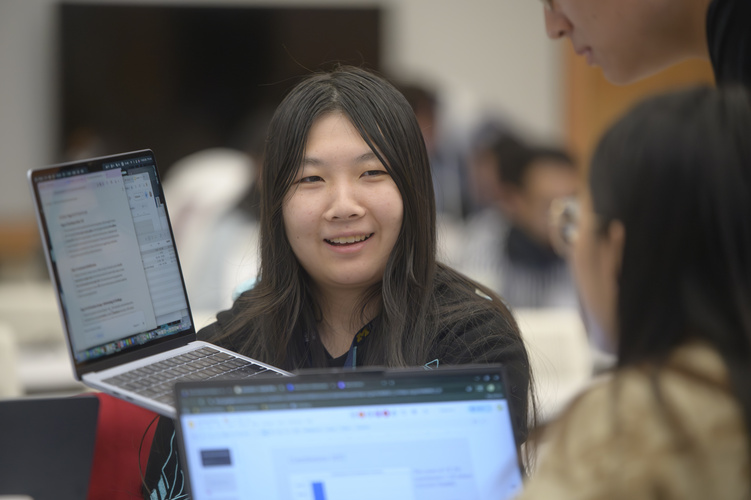A student holds up a laptop to show something to a peer