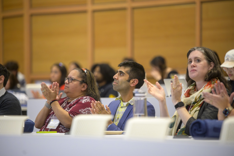 Three judges sit on a panel, clapping with thoughtful looks on their faces