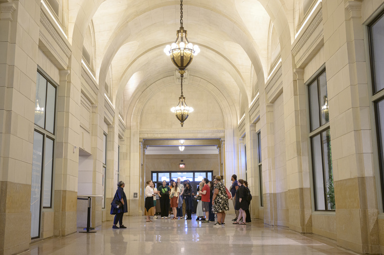 A view of the inside of Michigan Central, with tall ceilings hung with chandeliers and students gathered in the distance