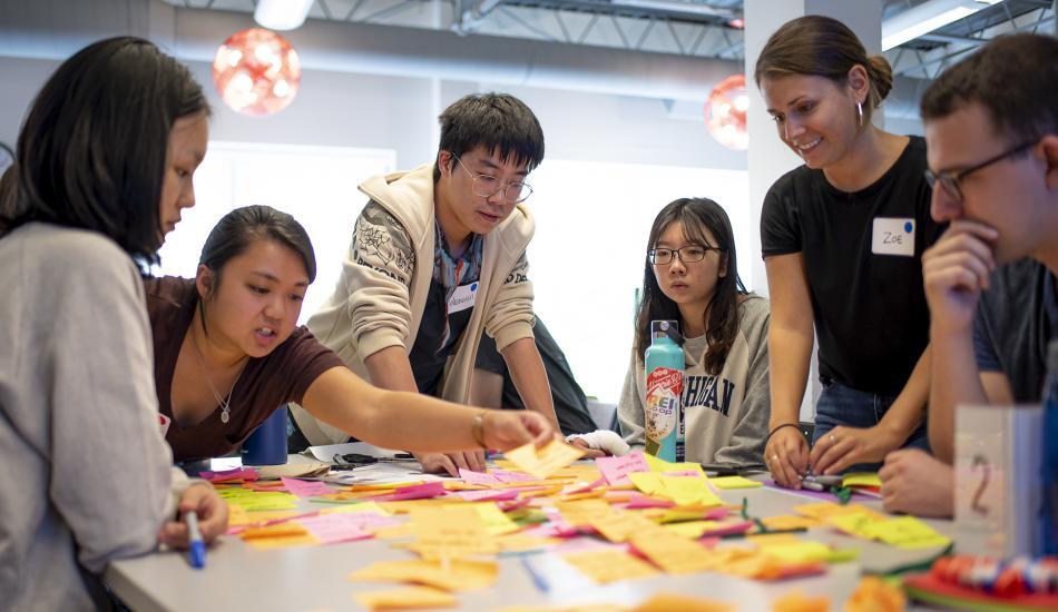Students Gathered around a table filled with sticky notes