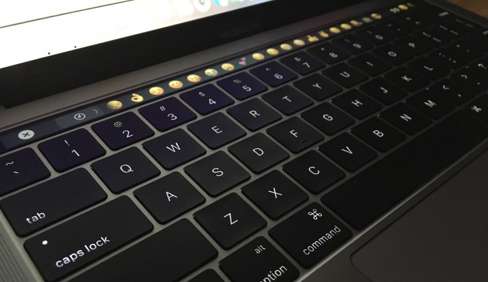 Laptop keyboard with a line of emoji choices on the touch bar.