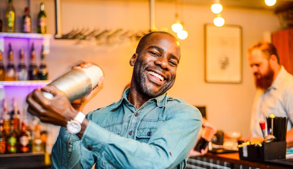 Eugene Yiga holding a cocktail shaker at a bar