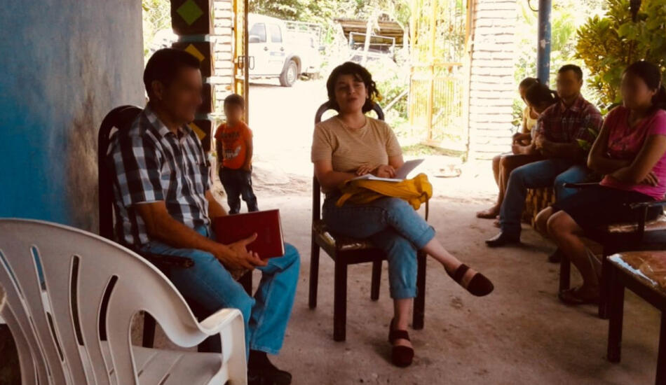 Sylvia in Honduras sitting in a plastic chair talking with residents.