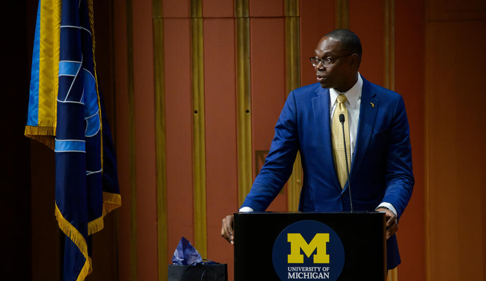 Lt. Gov. Garlin Gilchrist II stands at a podium adorned with the University of Michigan logo