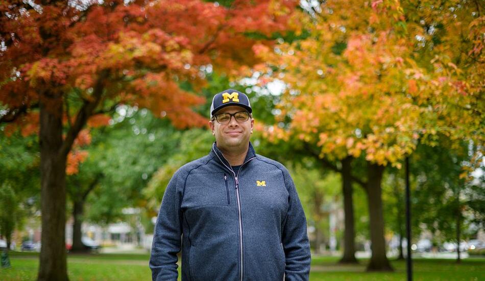 A photo of Kyle Bylin standing on campus with fall foliage behind him.