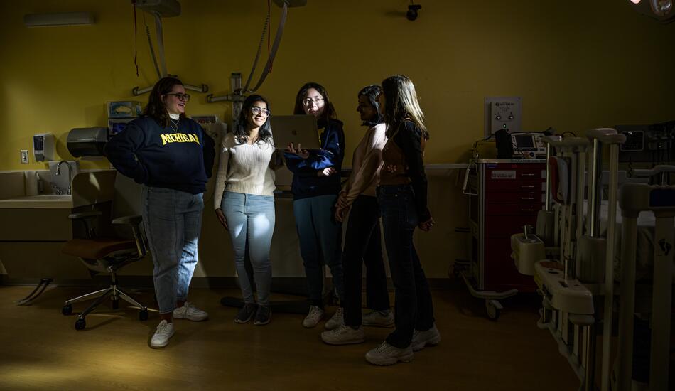 A photo of five students standing in a darkened operating room.