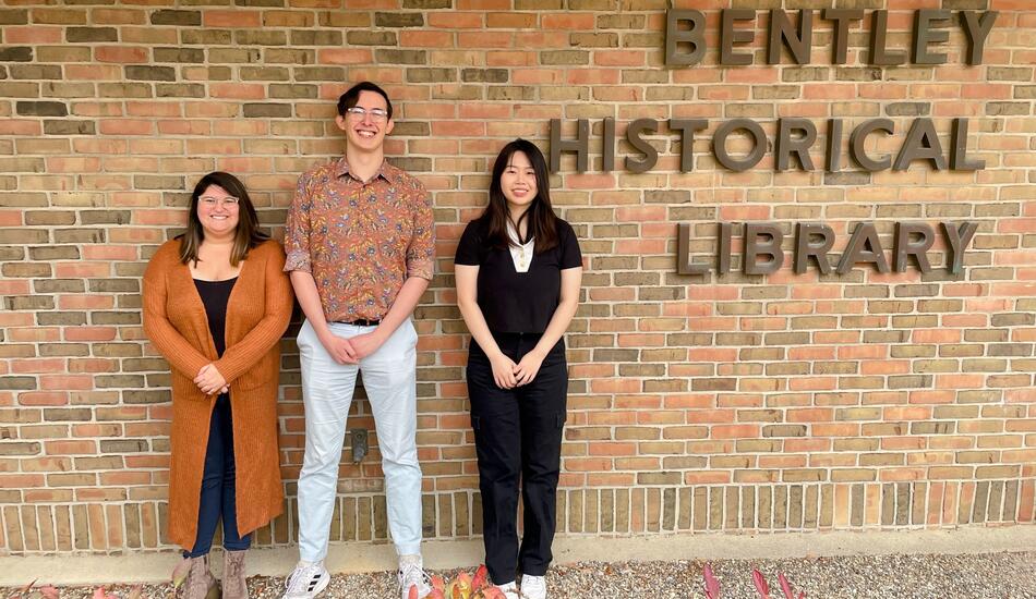 Stephanie Vettese, Clayton Zimmerman and Ziyan Zhou pose as a team in front of the Bentley's brick exterior, which reads "Bentley Historical Library"