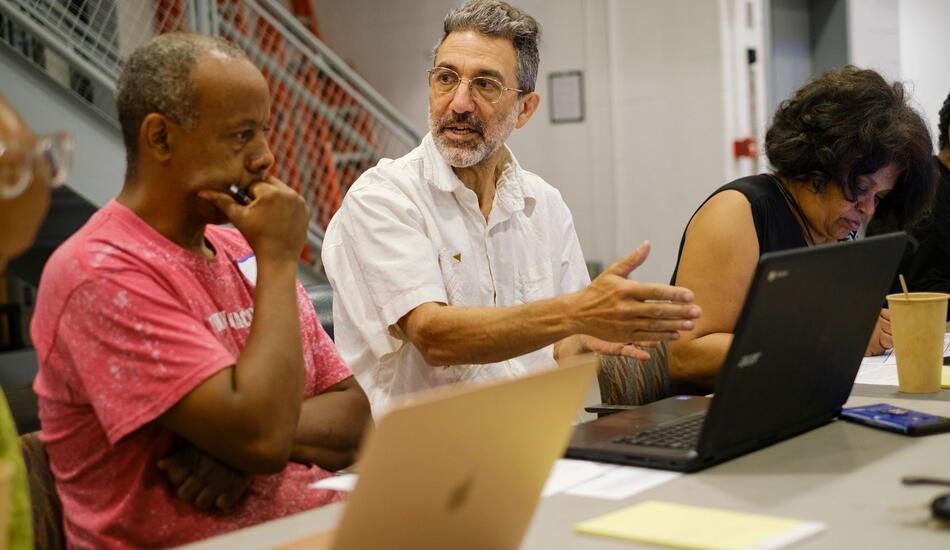 Ron Eglash sits at a laptop talking to others