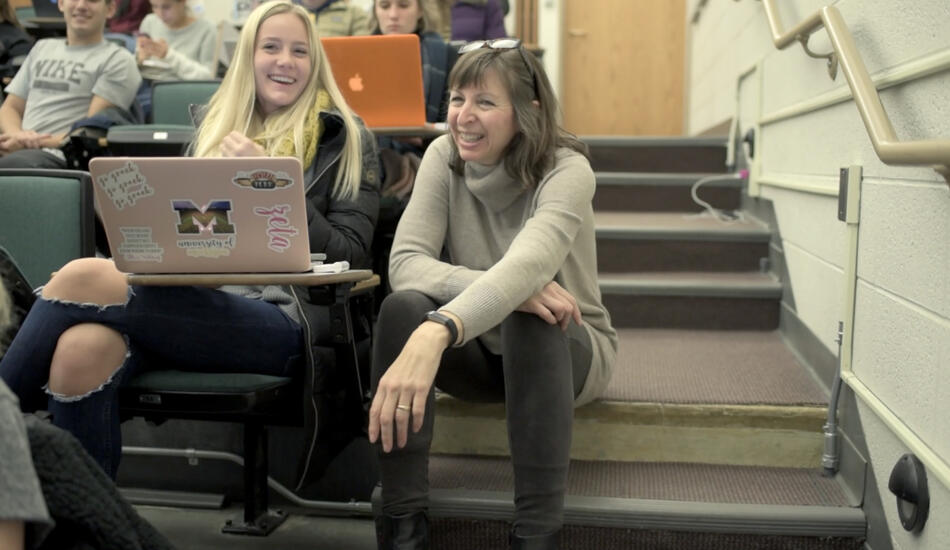 Barb sits next to a student in a classroom