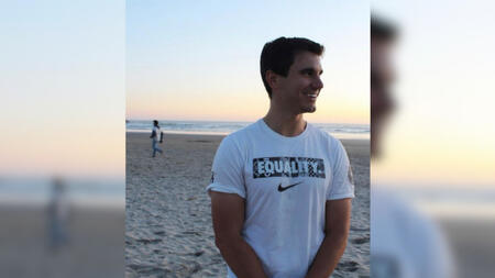 Kyle Balog on a beach at sunset looking off to the right.