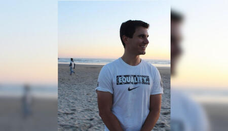 Kyle Balog on a beach at sunset looking off to the right.