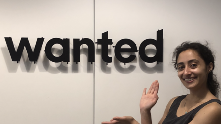 Salma Siddiqui posing next to a sign displaying the "wanted" logo. 