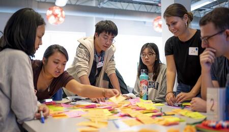 Students Gathered around a table filled with sticky notes