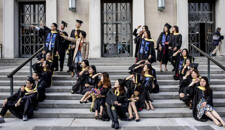 UMSI students in their graduation gowns sitting in an M shape on stairs