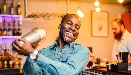 Eugene Yiga holding a cocktail shaker at a bar