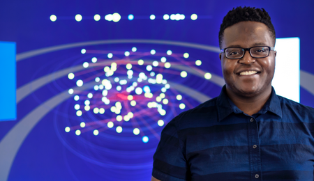 A student standing in front of a colorful data visualization 