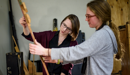Two students looking at a wooden artifact.