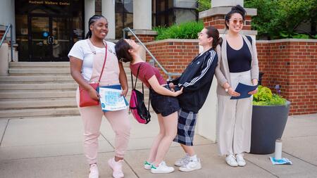Community college students touring the U-M campus make the Michigan “M” by posing as different parts of the letter in front of the Huetwell Visitors Center.