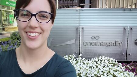 Maria Bronson in front of a OneMagnify sign.