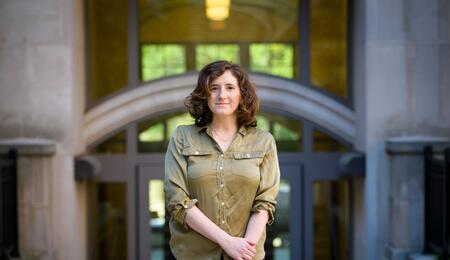 Assistant professor Abigail Jacobs stands in front of an academic building on the University of Michigan campus.