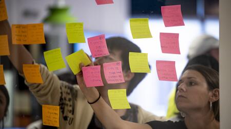 People putting sticky notes up on a transparent wall