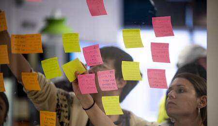 People putting sticky notes up on a transparent wall