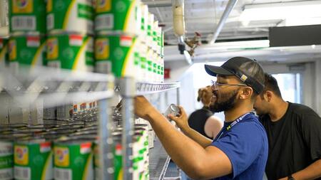 People stacks cans on a shelf full of similar cans