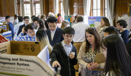 Students show a UMSI board member their poster at the 2023 UMSI Student Project Exposition