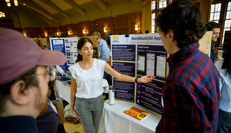 A student discussing a poster with two other people