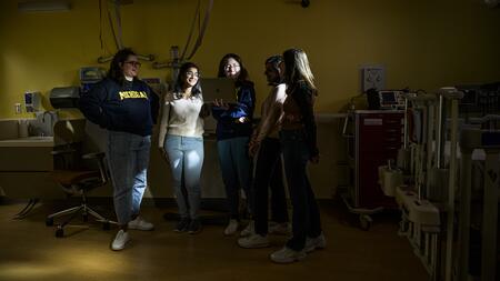 A photo of five students standing in a darkened operating room.