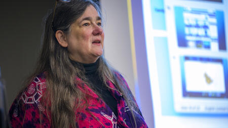 A close-up of Rochelle Sturtevant with part of an on-screen presentation visible behind her