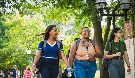 Students walk through the U-M campus near academic buildings on a tour.