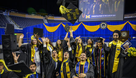 A group of students in graduation regalia throwing their mortar boards in the air.