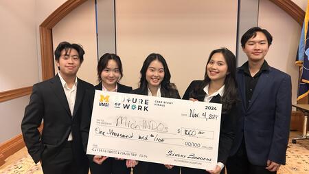 Five students hold a giant check made out to "MichIndos"