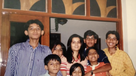 Eight cousins pose together for a photo, with a young RJ Jain wearing an orange shirt