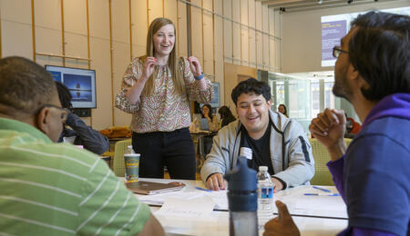 Career coach Jordan Hansen gestures excitedly at a table with three students