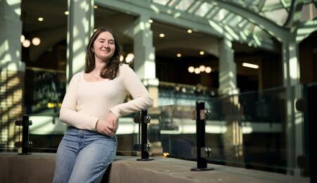 Charlotte Parent poses against a glass railing over the atrium of a building