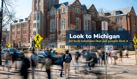 A graphic with a logo that says "Look to Michigan for tech solutions that put people first" over an image of students crossing State Street in front of the Michigan Union on a clear spring day. The students give the illusion of moving very quickly as a result of a long exposure photo, causing them to all have a heavy trail of motion blur.