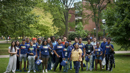 Students pose on a green lawn wearing Information Changes Everything t-shirts, with Sandra Lopez in the front right wearing yellow