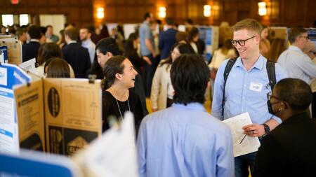 A group of students and faculty chatting at a poster fair.