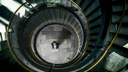 Overhead view of Kentaro Toyama standing at the center of a circular spiral staircase, looking up. 
