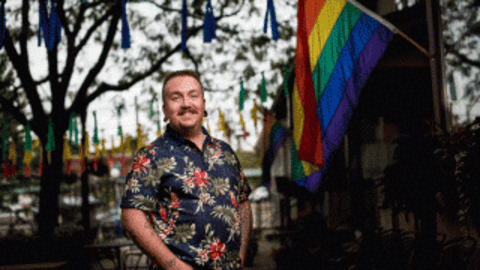 Jean Hardy outdoors in front of a pride flag