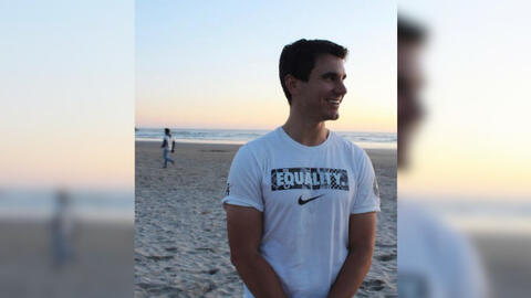Kyle Balog on a beach at sunset looking off to the right.