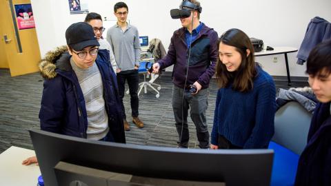 Michael Nebeling wearing a VR helmet and working with students in SI 659: AR/VR experiences