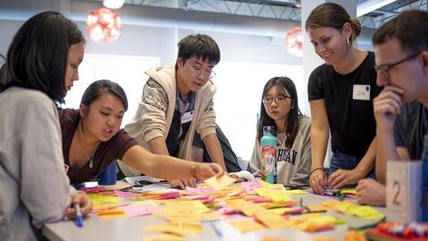 Students Gathered around a table filled with sticky notes