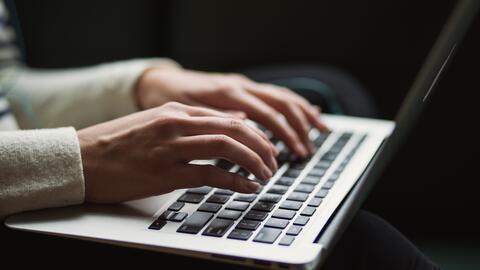 Hands typing on a laptop keyboard