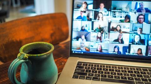 A coffee cup placed next to a laptop with Zoom open on the screen.