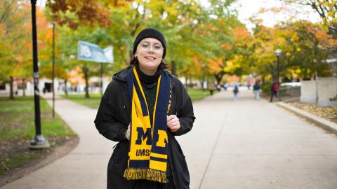Lucie Tatouskova standing on the University of Michigan Diag and wearing a maize and blue UMSI scarf.