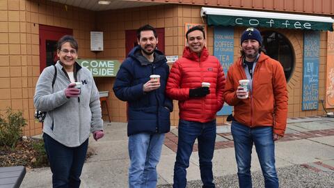 MADS students Stacey Bruestle, Stephen Ontko, David Hernandez and Daniel Best holding to-go coffees outside a coffee shop